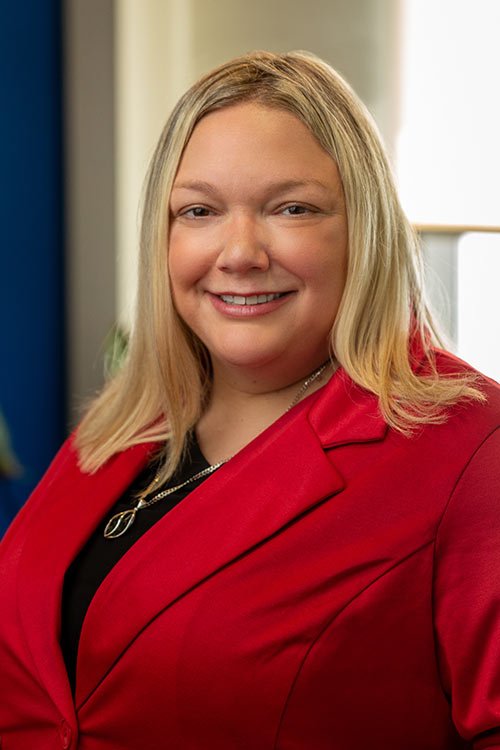 Professional headshot of Amanda Lang, a blonde woman, smiling, wearing a bright red blazer